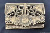 Front view of brass stamp holder showing ornate sunflower and leaf design