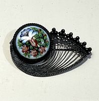 Front view of brooch showing floral porcelain cabochon and filigree metal design