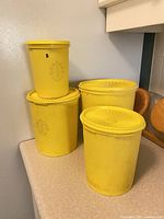 Front view of four yellow Tupperware canisters stacked, lids visible
