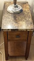 End table top showing faux marble laminate surface, drawer front, lamp for scale