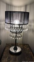 Lamp close-up showing shade, bulb, upper crystal ring, chrome stem and base