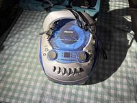 Top view of Memorex blue/silver boombox showing CD lid, controls and attached power cord