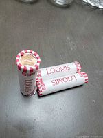 Three sealed Loomis penny rolls on table