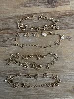 Four gold-tone charm bracelets laid out showing overall style and charms