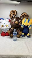 Group shot of all three plush toys with water bottle for scale