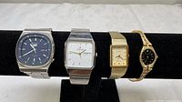 All four wristwatches on display bar showing fronts and bracelets