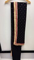 Full length of black saree showing gold zari and pink border with embroidered dots