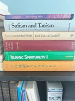 Full stack of six books on shelf showing spine titles and colours