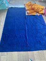 Full view of navy velvet fabric panel laid on floor, partial view of orange sari fabric