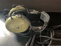 Side view of olive green ear cups with logo and cable