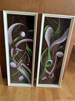Both framed velvet paintings standing side by side