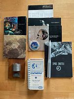 Group view of books, manuals, satellite model, rocket model, patch and record