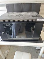 Front view of black 6U wall-mount rack cabinet showing glass door and key lock