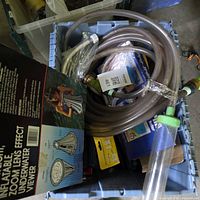 Blue bin with coiled transparent pool hose, underwater viewer tube, packaged plumbing fittings visible