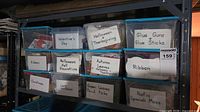 Shelf holding labelled clear tubs for Valentine's Day, Halloween, glue guns, ribbon, floral picks etc.