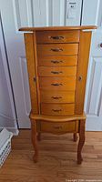 front view of honey light oak jewelry armoire, drawers closed