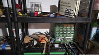 Overall view of lot on shelving showing boxed clamp set, Jobmate bit set, staple gun box, hardware organizer and loose tools