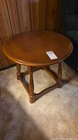 Side view of round medium-brown end table beside chair