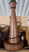 Lamp base in box showing wood-grain brown metal cone design and power cord