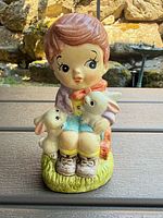 Front view of ceramic boy coin bank holding rabbits