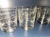 Six etched glass tumblers grouped on shelf