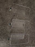 three clear plastic lids or bins laid flat showing handles