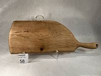 Front view of maple whale-shaped charcuterie board on stand
