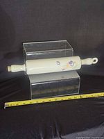 Full view of porcelain rolling pin with floral design and tape measure showing length