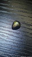 Pear cabochon black star sapphire on textured surface showing star effect