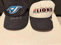 Front view of both caps showing team logos and autograph