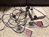 Console, two controllers and cables on carpet
