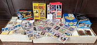 Overall view showing two long boxes packed with cards, several boxed sets and wax packs, binder pages with star cards spread out