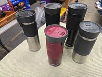 Six Contigo travel mugs grouped on table