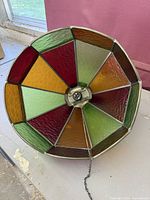 underside view showing multicolour stained glass panels, socket, and chain