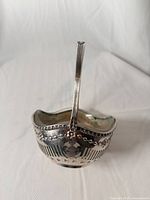Front view of silver-plated sugar basket with handle upright