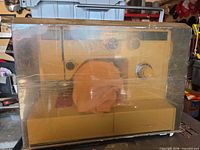 Sewing machine inside hard cover, wrapped in plastic