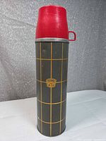 Front view of gray Thermos bottle with yellow grid and red lid