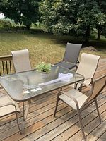 rectangular glass-top patio table with four chairs visible