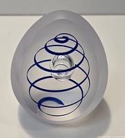 Front view of frosted glass egg paperweight showing internal blue spiral and central bubble