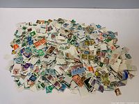 Pile of loose multicolor postage stamps scattered on surface