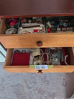Open drawers showing thread spools, yarn, patterns, lamp parts, assorted sewing and knitting supplies