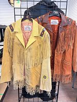 Front view of both suede jackets on rack