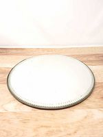 Front view of round mirror showing reflective surface and scalloped bevel