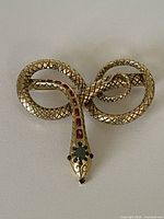Front view of coiled snake brooch showing scale texture and stone insets