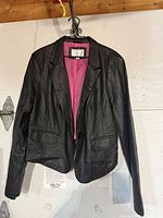 Front view of black faux leather blazer with pink lining