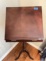 Top view of square cherry-finish tilt-top table showing surface wear and pedestal base