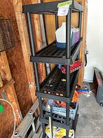 Full view of the four-tier black plastic shelving unit