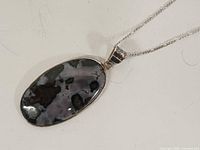Front view of oval moss agate pendant on silver chain