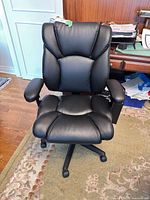 Front view of black faux leather office chair showing seat, backrest, arms and base