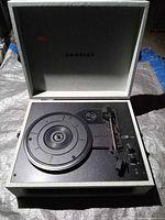 Record player open showing platter, tonearm, controls and Crosley logo